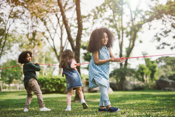 Happy children playing tug of war at the park - Photo, Image