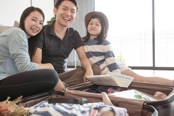 Happy Asian family is preparing for travel at home .Mom daughter and father are packing suitcases for the trip. - 写真・画像