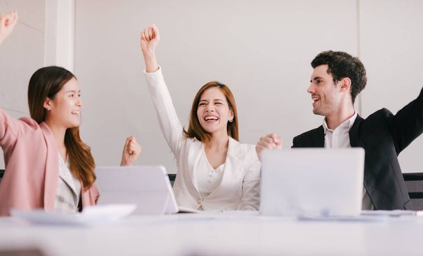 Team of successful business people is celebrating the receiving of positive answer from the investors. Group of young entrepreneurs are happy with the good news from the business partners. - Foto, imagen
