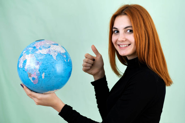 Portret szczęśliwej młodej kobiety trzymającej w rękach geograficzny glob świata. Cel podróży i koncepcja ochrony planety. - Zdjęcie, obraz