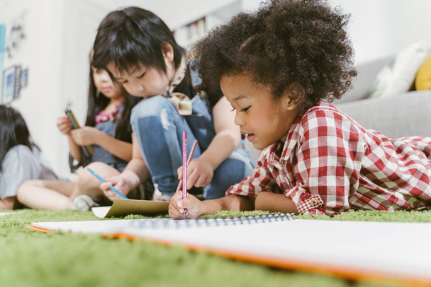 Grupo de niños preescolares pequeños dibujando papel con lápices de color. retrato de chica africana con amigos concepto de educación
. - Foto, Imagen