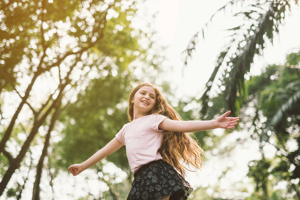Молодая девушка с распростертыми объятиями наслаждается свободой в парке так счастливо расслабиться танец
 - Фото, изображение