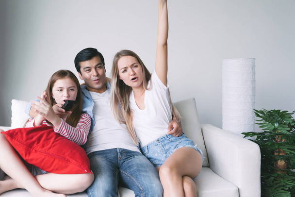 boldog család együtt tévézik a kanapén a nappaliban. család és otthon fogalma - Fotó, kép