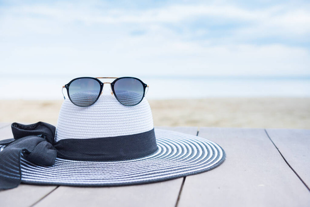 Women hat on the beach. Summer vacation with space on blue sky background. - Foto, imagen