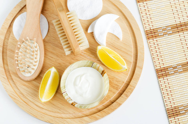 Fresh greek yogurt, lemon, cotton eye patches, wooden hair brush and body brush. Ingredients for preparing homemade face and hair masks. Natural skin care recipe and zero waste concept. Top view, copy space - Foto, immagini