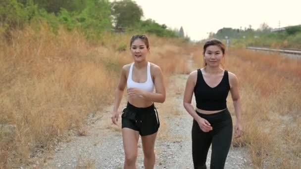 Lassú mozgású atléta nő fut a barátjával. Ázsiai női futó állóképesség képzés nyáron. Heathy életmód és sport koncepció. - Felvétel, videó