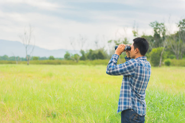 Pozorování ptáků v lese s přirozeným zázemím. Turista drží dalekohled. Venkovní aktivity a rekreace na letní dovolené. - Fotografie, Obrázek