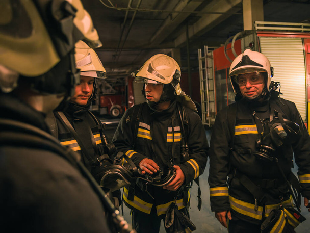Grupo de bombeiros com uniforme dentro do quartel de bombeiros preparando-se para resgate seguro - Foto, Imagem