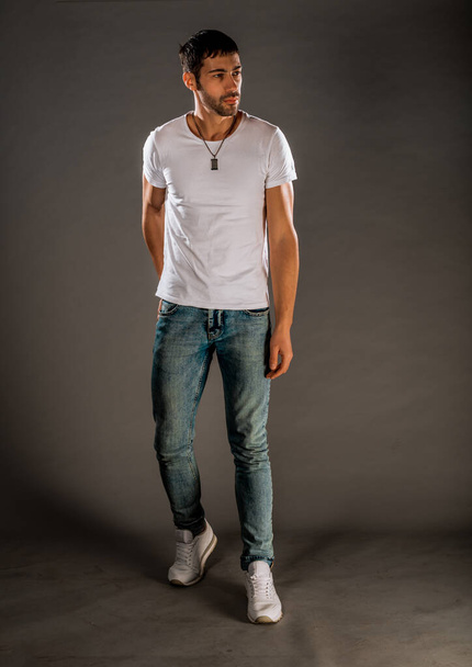 Cool handsome guy wearing stylish blue jeans, white t-shirt and sneakers - Photo, Image