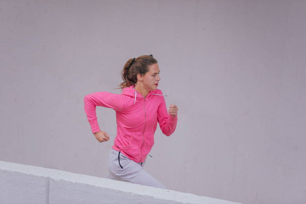 Corredor femenina joven y saludable durante una rutina de entrenamiento urbano - Foto, imagen