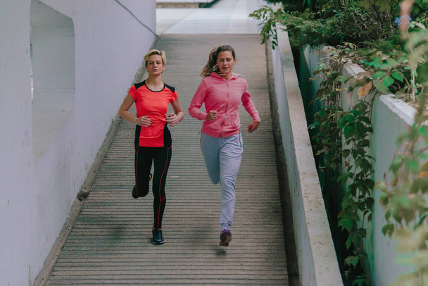 Две привлекательные спортсменки бегают в городской среде
 - Фото, изображение