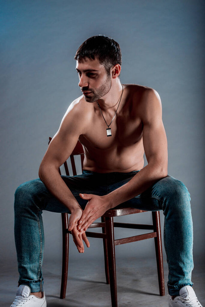 Torso záběr sexy muž bez trička pózující na dřevěné židli - Fotografie, Obrázek
