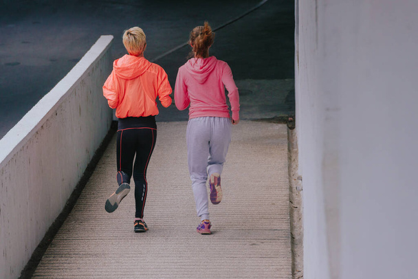 Young healthy female ahtletes exercising with a run in the city - Foto, Imagen