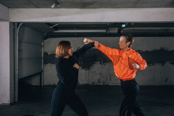 Two female athletes showing technical skills while practicing fighting in a garage - Photo, Image