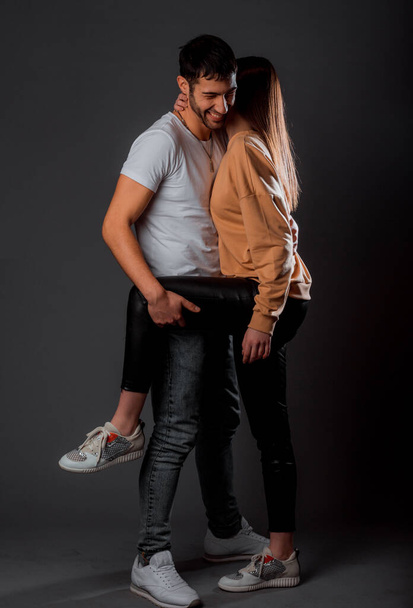 Romantic guy and girl in trendy clothes gently touching and cuddling - Foto, afbeelding