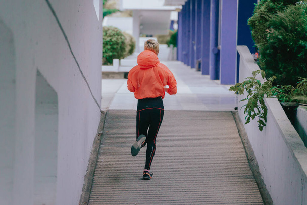 Attractive female athlete doing a running exercise in an urban environment - Foto, imagen