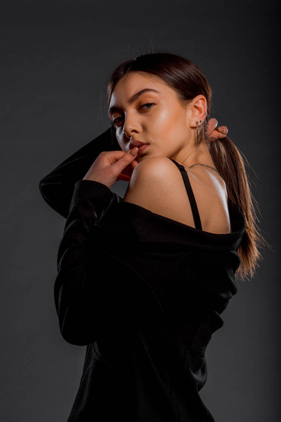 Studio fashion portrait of a modern girl wearing black clothes against grey wall - Photo, Image