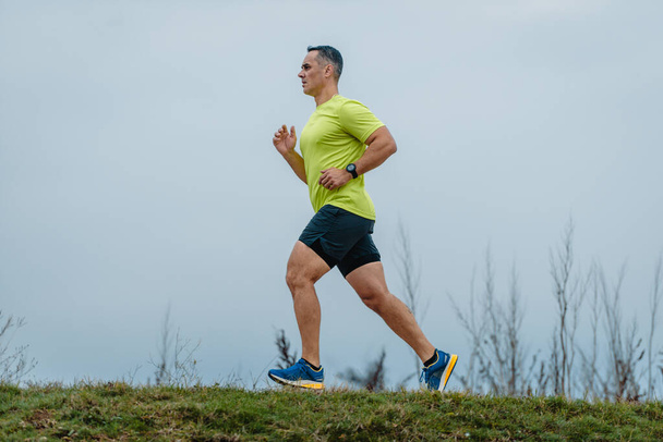 40 yaşın üstündeki formalı adam koşu egzersizi sırasında etek giyiyor. - Fotoğraf, Görsel