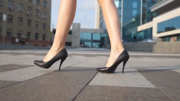 Pés de mulher de negócios jovem em calçado em salto alto que vai na rua urbana. Pernas femininas finas em sapatos pretos em saltos altos andando na praça da cidade. Menina elegante pisando para o trabalho. Lento movimento Fechar
 - Filmagem, Vídeo