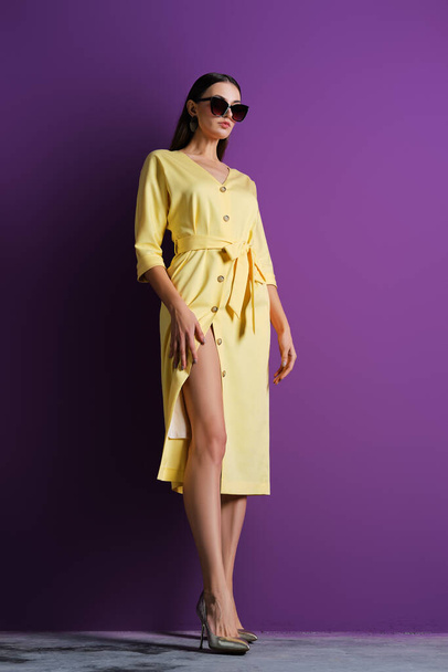 Fashion model in big sunglasses wearing yellow dress with unfastened buttons - Fotografie, Obrázek