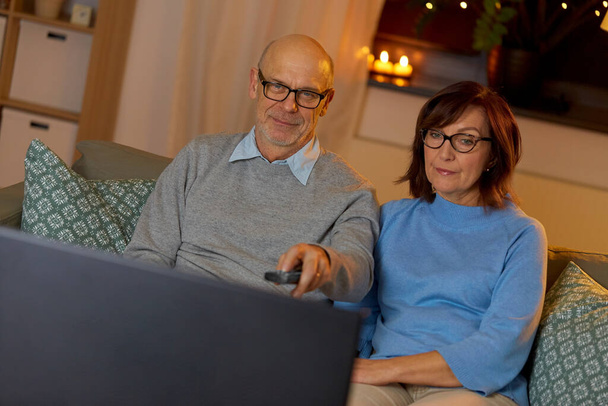 senior couple watching tv at home in evening - Фото, изображение