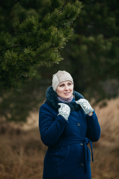 Ritratto di donna carina europea lettone dall'aspetto felice e sorridente Indossa pelliccia sintetica e cappotto e copricapo blu scuro - Foto, immagini