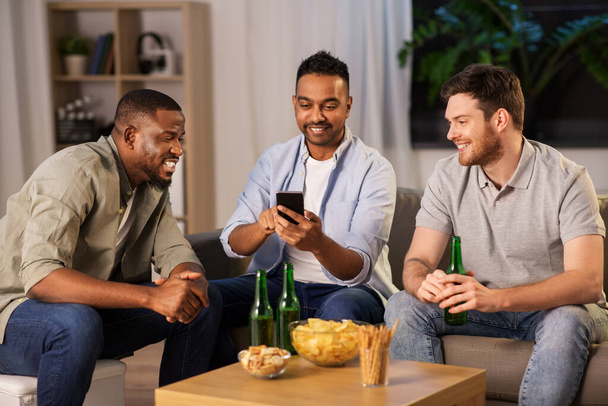male friends with smartphone drinking beer at home - Foto, Imagen
