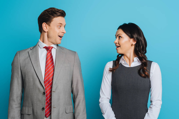 two surprised businesspeople looking at each other on blue background - Foto, Imagem