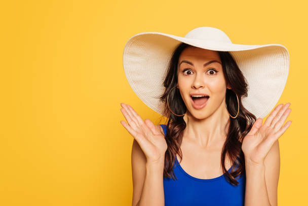 attractive, surprised woman in sun hat showing wow gesture isolated on yellow - Photo, Image