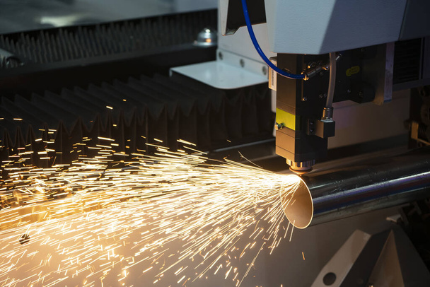 De vezel laser snijmachine snijden van de roestvrij stalen buis controle door CNC-programma. De plaatbewerking door lasersnijmachine maakt de gravure in de roestvrijstalen pijpdelen. - Foto, afbeelding