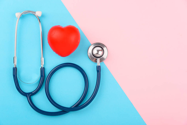 Doctor's Day concept, flat lay top view, stethoscope with red heart on pink blue background, diagnosis of heart disease with copy space for text - 写真・画像