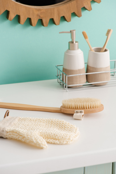 Hygiene products on shelf near massage brush and bath glove in bathroom, zero waste concept - Photo, Image