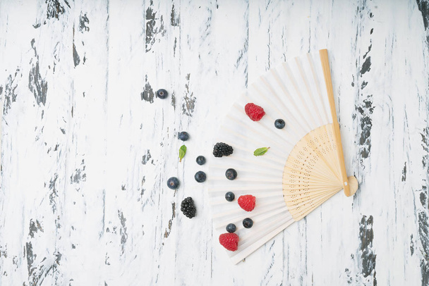 Fan decorated with Ripe and juicy fresh berries over white rustic wooden backgrounds. Blueberry, Raspberry and Blackberry. Top view - Fotografie, Obrázek
