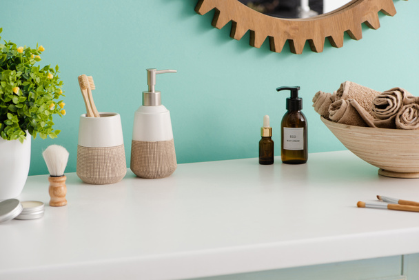 Various hygiene and cosmetic products, bowl with towels and flowerpot in bathroom, zero waste concept - Foto, afbeelding