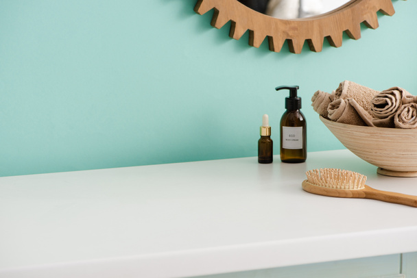 Hajkefe, üveg öko-testápoló krém és olaj, tál törölközővel a tükör közelében a fürdőszobában, nulla hulladék koncepció - Fotó, kép