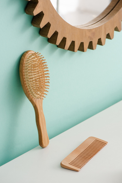 Cepillo de pelo con peine y espejo redondo en la pared turquesa en el baño, concepto de cero residuos
 - Foto, Imagen
