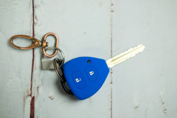Blue car remote key cover silicone with chain on wooden table. - Photo, Image