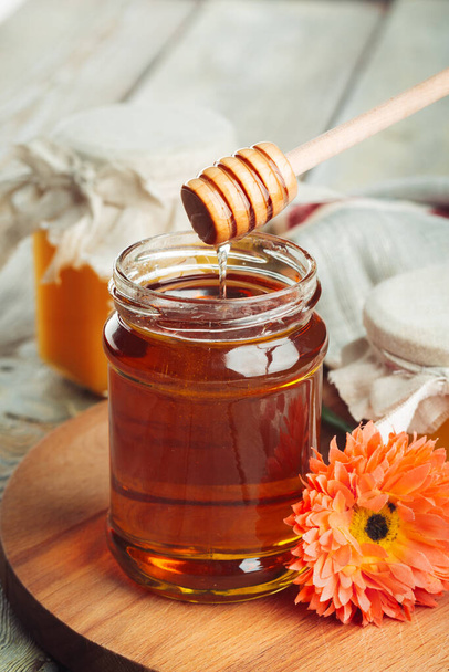 Honey background. Sweet honey in glass jar on wooden background. - Fotografie, Obrázek