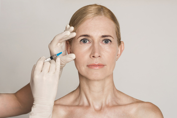 Plastiikkakirurgia. Keski-ikäinen nainen, joka vastaanottaa Botox-injektion - Valokuva, kuva