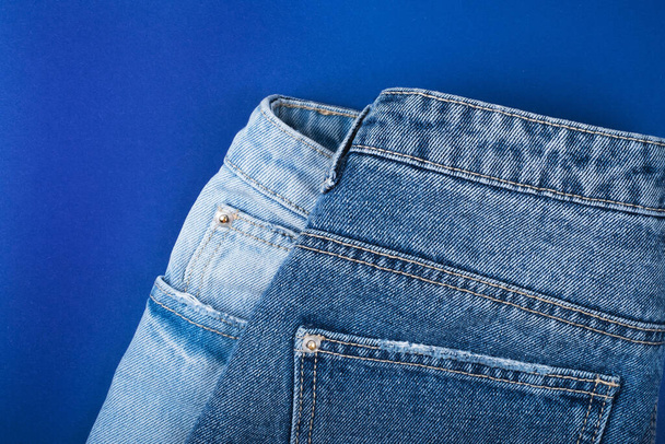Пара джинсов изолированы на синем фоне
. - Фото, изображение