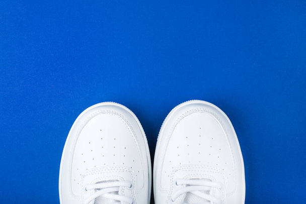 Flatlay with white sneakers isolated on blue background. - Photo, Image