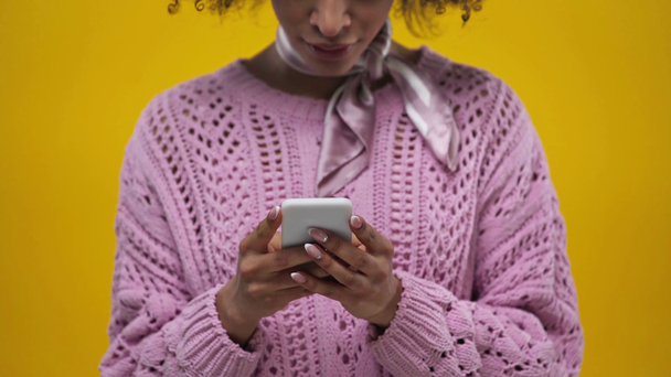 vista recortada de chica afroamericana usando teléfono inteligente aislado en amarillo
  - Imágenes, Vídeo