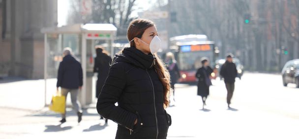 COVID-19 Young woman in city street wearing face mask protective for spreading of Coronavirus Disease 2019. Panoramic banner view of girl with surgical mask on face against SARS-CoV-2. - Foto, afbeelding