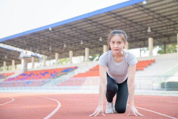Ázsiai aranyos sportoló egy versenypályán készen áll a futásra, futó és sport koncepció - Fotó, kép