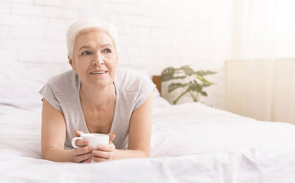 Senior signora godendo di caffè caldo fresco, a riposo a letto
 - Foto, immagini