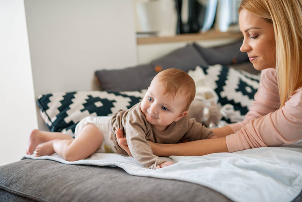 Happy family.Mother and baby boy playing and smiling on bed in living room.Family,happiness and love concept. - Photo, Image
