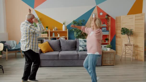 Carefree senior people couple dancing at home relaxing having fun with modern music - Metraje, vídeo