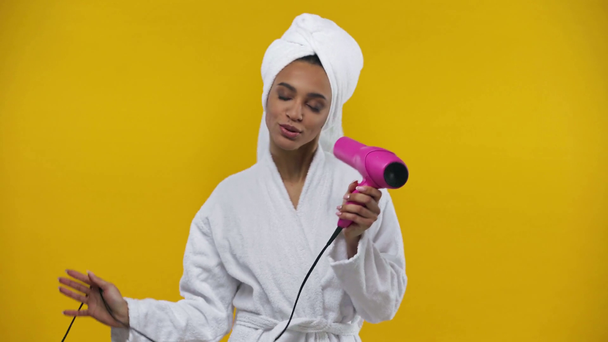 menina afro-americana segurando secador de cabelo isolado no amarelo
  - Filmagem, Vídeo