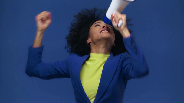 chica afroamericana gritando en megáfono aislado en azul
 - Metraje, vídeo