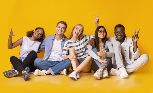 Carefree teenagers having fun over yellow studio background - Foto, immagini
